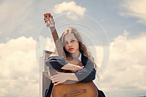 Small music lover. free music content. Teenage musician playing guitar. Portrait of little kid playing guitar on sky