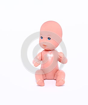 A small naked doll sits on an isolated white background. Close-up