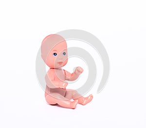 A small naked doll sits on an isolated white background. Close-up