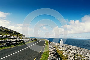 Small narrow asphalt road by Atlantic ocean, Black Head Lighthouse area, Burren, Ireland.