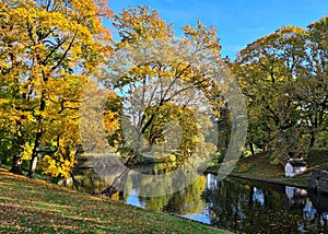 Small narrow canal in city park on quiet sunny autumn day