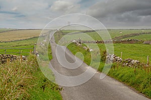 Small narrow country road to Moher Tower at Hag`s Head, county Clare, Ireland. Selective focus. Beautiful cloudy sky. Background
