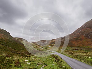 Small narrow road in a stunning mountain area. Mamore gap, county Donegal, Ireland. Amazing drive with rough wild nature scenery.