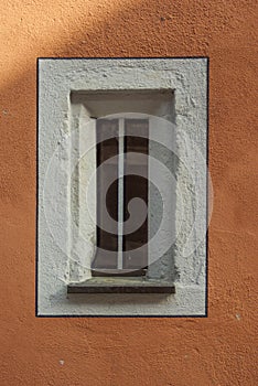 Small narrow window in an old restored building with new painted facade