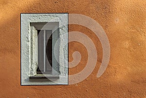 Small narrow window in an old restored building with new painted facade