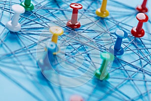 Small network of colorful pins and string, An arrangement of colorful pins linked together with string on a blue background