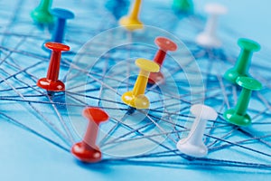 Small network of colorful pins and string, An arrangement of colorful pins linked together with string on a blue background