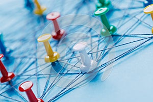 Small network of colorful pins and string, An arrangement of colorful pins linked together with string on a blue background