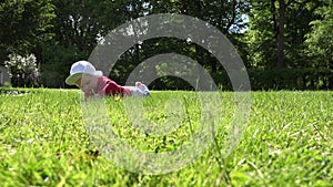 Small newborn baby lay on lawn grass and research it. 4K