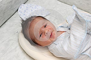 A small newborn boy 7 days in the hospital Looking at the camera. Hair dark skin dark