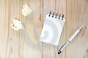 Small note book paper notepad for writing information with pen and crumpled paper balls on wooden table