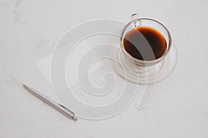 Small notebook with blank area for text or message on brown cover and coffee cup on table in morning time