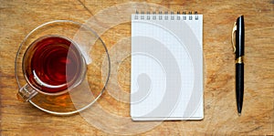 Small notebook with a Cup of tea, stick on a rustic wood background.