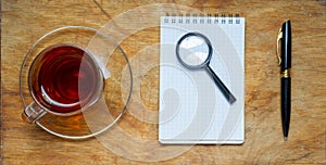 Small notebook with a Cup of tea, stick on a rustic wood background.