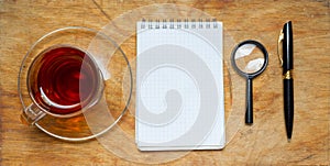 Small notebook with a Cup of tea, stick on a rustic wood background.
