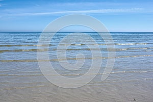 Small ocean waves on the shore against a clear blue sky with copy space. Landscape of the wide open sea or beach with