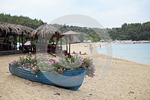 Small Old blue boat full of flowers on the beach