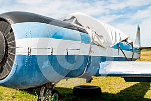 Small old blue plane standing in summer field