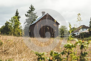 Small, old, brown barn in rural neighborhood