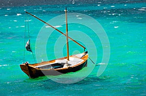 small and old fishing wooden boat with nobody on board sailing in the green Aegean sea. The wooden boa is waiting at harbor