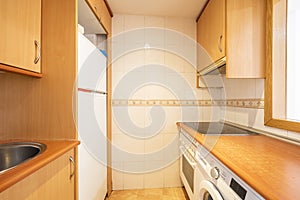 Small old kitchen with cherry-colored furniture from an apartment with a serving hatch and white appliances