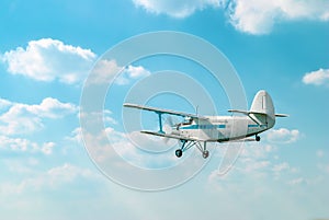 Small old private plane flying in light white clouds