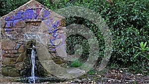 A small old stone structure from which water pours