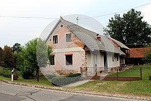 Small old suburban family house with broken facade and dilapidated windows surrounded with freshly cut grass and trees