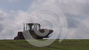 Small old tractor fertilize farm crop field in spring