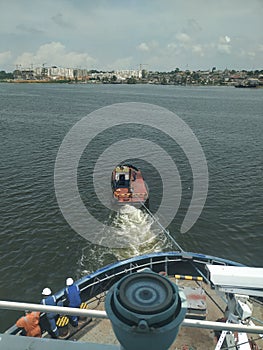 Small and old tugboat towing a large vessel to a port to offload cargo