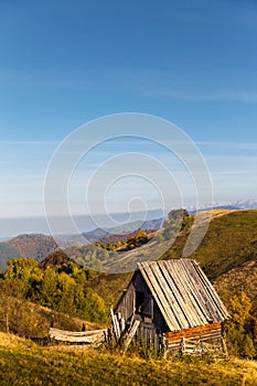 Small old wooden abandoned shepherds house on hill against mountain landscape. Carpathian Mountains, Paltinis, Romania