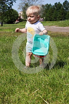 Small one year old boy child playing with toy truck car in the park