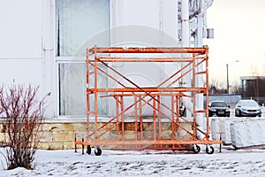 small orange building mobile work scaffolding near a large sports complex.