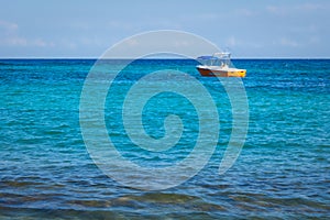 Small orange fishing boat, tourist boat in open water. Tropical turquoise blue sea background.