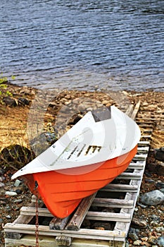 Small orange rowboat moored at riverside in northern Sweden