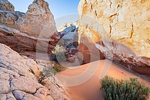 A small orange sand dune between massive sandstone rock formations