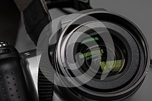 A small ordinary camera with a built-in zoom lens. Close to the glass. Glare and details. The concept of digital photography and