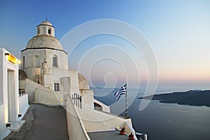 Small orthodox church with Greek flag at sunset,Santorini,Greece