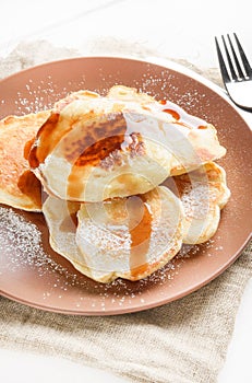 Small pancakes with honey on ceramic plate
