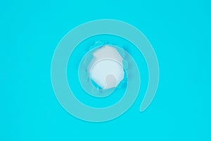 Small paper hole with torn sides over blue background for your text