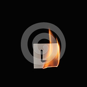 Small paper with letter L burning on a black background