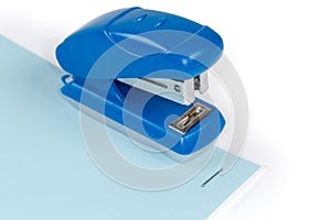 Small paper stapler on a stapled white and blue sheets