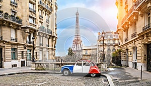 small paris street with view on the famous paris eifel tower on a cloudy rainy day with some sunshine - citroen 2CV in french