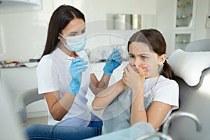 Small patient is afraid of dentist in modern dental clinic