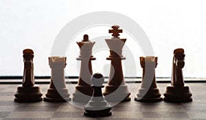 Small pawn on chess board against larger adversary concept of adversity ,discimination ,equality .focus on forground