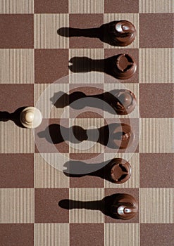 Small pawn on chess board outnumbered  against larger adversary concept of adversity ,discimination ,equality photo