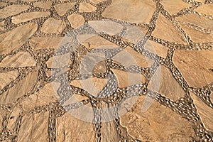Small pebbles among beige crushed paving stones, tiled stone floor texture, seamless tile
