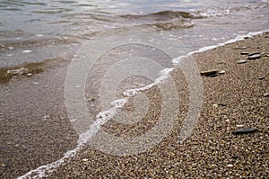 Small pebbles and wet sand on the sea beach; water line.