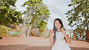 A small philippine schoolgirl shows spinning spinners. Tropical landscape. Summer. Childhood.