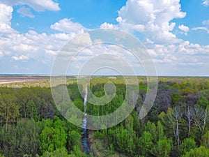 Small picturesque forest river, aerial view. Beautiful cloudy sky over the forest